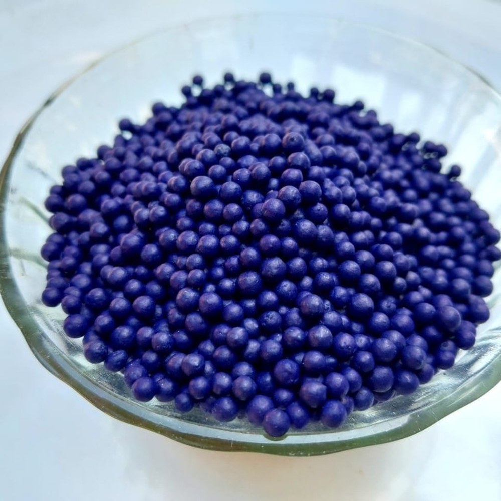 Purple blue coated organic fertilizer granules in glass bowl